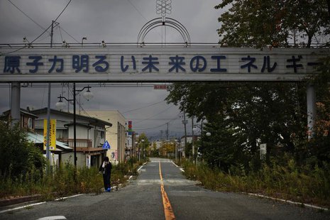 A woman, who came for a brief visit to her home, walks under a sign reading "Nuclear Power - The Energy for a Better Future", at the entranc A woman, who came for a brief visit to her home, walks under a sign reading "Nuclear Power - The Energy for a Better Future", at the entranc