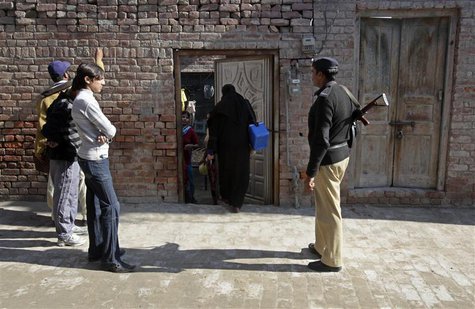 A policeman stands guard as female polio workers wait to give polio vaccine drops to children in Lahore December 20, 2012. REUTERS/Mohsin Ra A policeman stands guard as female polio workers wait to give polio vaccine drops to children in Lahore December 20, 2012. REUTERS/Mohsin Ra