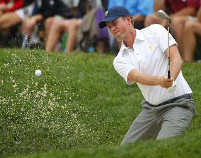 U.S. team member Webb Simpson hits from a bunker on the 14th hole as he plays International player Louis Oosthuizen of South Africa during t U.S. team member Webb Simpson hits from a bunker on the 14th hole as he plays International player Louis Oosthuizen of South Africa during t