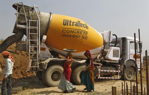 Workers walk in front of an UltraTech concrete mixture truck at the construction site of a commercial complex on the outskirts of the wester Workers walk in front of an UltraTech concrete mixture truck at the construction site of a commercial complex on the outskirts of the wester