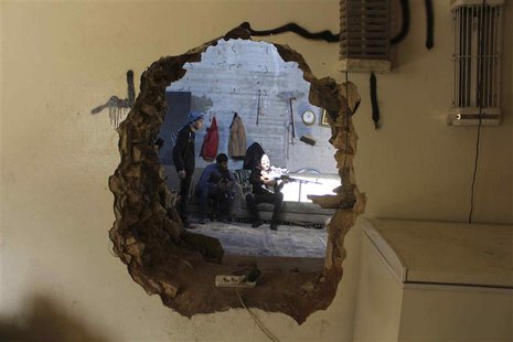 A Free Syrian Army fighter aims his weapon as he is seen through a hole in a wall in Aleppo's Karm al-Jabal district October 21, 2013. REUTE A Free Syrian Army fighter aims his weapon as he is seen through a hole in a wall in Aleppo's Karm al-Jabal district October 21, 2013. REUTE