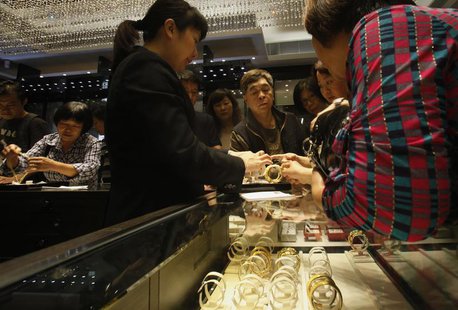 A sales attendant shows a gold bracelet to customers leaning over a half-empty display case at a jewellery store in Hong Kong April 26, 2013 A sales attendant shows a gold bracelet to customers leaning over a half-empty display case at a jewellery store in Hong Kong April 26, 2013