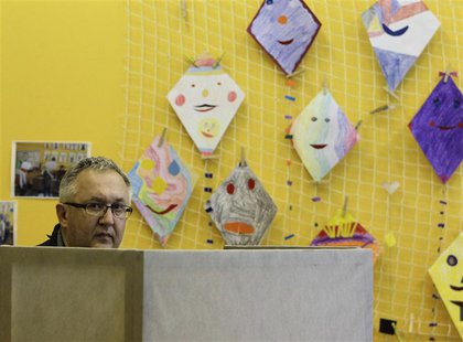 A man looks out from behind a booth before casting his vote at a polling station during an early general election in Brno October 25, 2013. A man looks out from behind a booth before casting his vote at a polling station during an early general election in Brno October 25, 2013.