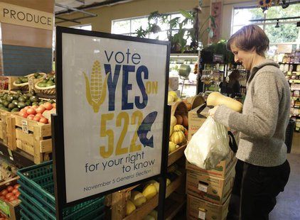 A customer picks up produce near a sign supporting a ballot initiative in Washington state that would require labelling of foods containing A customer picks up produce near a sign supporting a ballot initiative in Washington state that would require labelling of foods containing