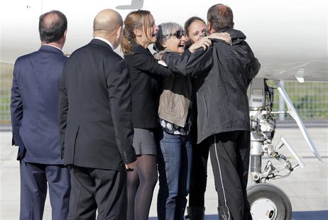 Former French hostage Daniel Larribe (R) is welcomed by relatives as French President Francois Hollande (L) and French Defence Minister Jean Former French hostage Daniel Larribe (R) is welcomed by relatives as French President Francois Hollande (L) and French Defence Minister Jean