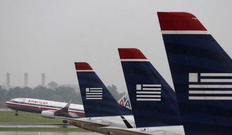 An American Airlines jet takes off while U.S. Airways jets are lined up at Reagan National Airport on the day U.S. Airways' stockholders are An American Airlines jet takes off while U.S. Airways jets are lined up at Reagan National Airport on the day U.S. Airways' stockholders are
