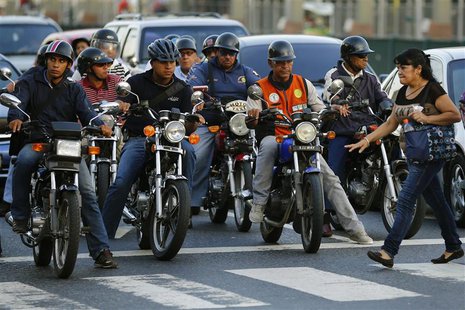 Motorcyclists wait for the traffic lights to change at a road junction in Caracas October 25, 2013. REUTERS/Jorge Silva Motorcyclists wait for the traffic lights to change at a road junction in Caracas October 25, 2013. REUTERS/Jorge Silva