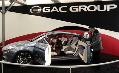 Two workers prepare GAC Motor's range-extended electric hybrid F-jet concept vehicle for display in Cobo Center in advance of media preview Two workers prepare GAC Motor's range-extended electric hybrid F-jet concept vehicle for display in Cobo Center in advance of media preview