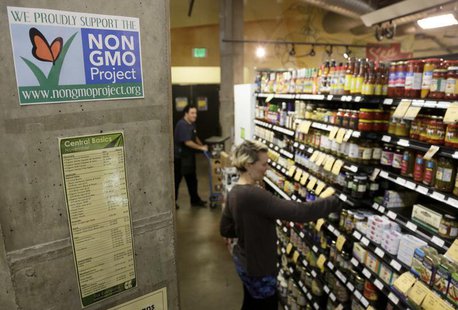 Employees stock shelves near a sign supporting non genetically modified organisms (GMO) at the Central Co-op in Seattle, Washington October Employees stock shelves near a sign supporting non genetically modified organisms (GMO) at the Central Co-op in Seattle, Washington October