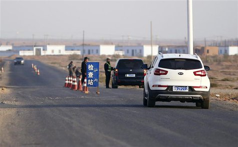 A police officer stops a car to check for identifications at a checkpoint near Lukqun town, in Xinjiang province in this October 30, 2013 fi A police officer stops a car to check for identifications at a checkpoint near Lukqun town, in Xinjiang province in this October 30, 2013 fi