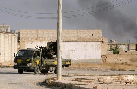 Forces loyal to Syria's President Bashar al-Assad drive a military vehicle carrying a picture of Assad on its windscreen as smoke rises in t Forces loyal to Syria's President Bashar al-Assad drive a military vehicle carrying a picture of Assad on its windscreen as smoke rises in t
