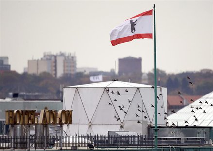Birds fly beside a white covered structure and a Berlin city flag next to the roof of the British embassy in Berlin, November 5, 2013. REUTE Birds fly beside a white covered structure and a Berlin city flag next to the roof of the British embassy in Berlin, November 5, 2013. REUTE