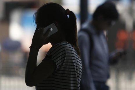 A woman speaks on her iPhone as she walks on a busy street in downtown Shanghai September 10, 2013. REUTERS/Aly Song A woman speaks on her iPhone as she walks on a busy street in downtown Shanghai September 10, 2013. REUTERS/Aly Song