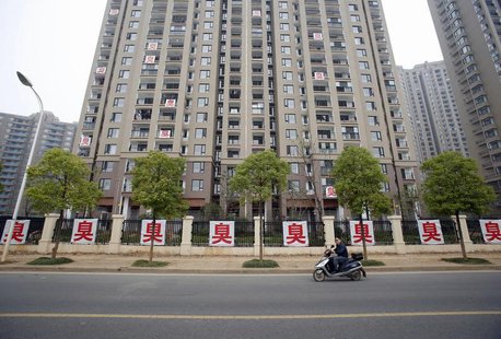 A motorist rides past banners hanging outside a residential community in Wuhan, Hubei province, October 21, 2013. REUTERS/Stringer A motorist rides past banners hanging outside a residential community in Wuhan, Hubei province, October 21, 2013. REUTERS/Stringer