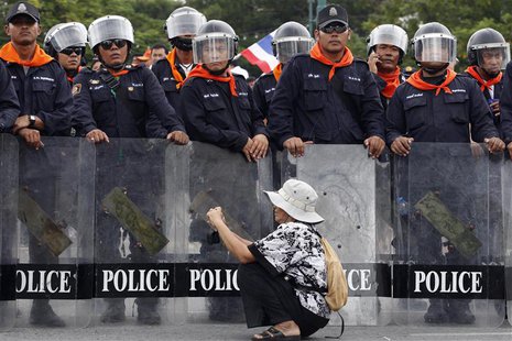 A woman takes pictures in front of a line of policemen blocking protesters against an amnesty bill, on the main road near the government and A woman takes pictures in front of a line of policemen blocking protesters against an amnesty bill, on the main road near the government and
