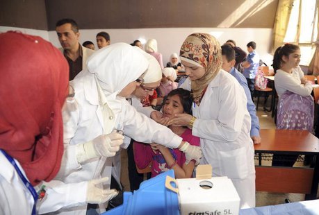 Syrian health workers administer polio vaccination to a girl at a school in Damascus, in this file photo taken by Syria's national news agen Syrian health workers administer polio vaccination to a girl at a school in Damascus, in this file photo taken by Syria's national news agen