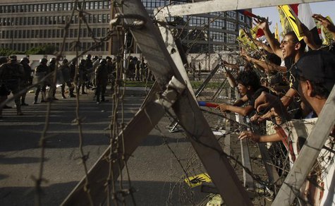 Members of the Muslim Brotherhood and supporters of ousted Egyptian President Mohamed Mursi shout slogans next to barbed wire as army soldie Members of the Muslim Brotherhood and supporters of ousted Egyptian President Mohamed Mursi shout slogans next to barbed wire as army soldie
