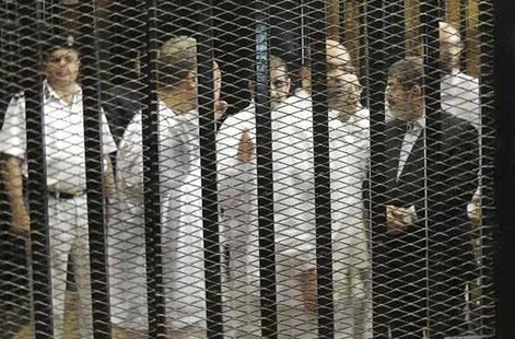 Ousted former Egyptian president Mohamed Mursi (R) speaks with other senior figures of the Muslim Brotherhood in a cage in a courthouse on t Ousted former Egyptian president Mohamed Mursi (R) speaks with other senior figures of the Muslim Brotherhood in a cage in a courthouse on t
