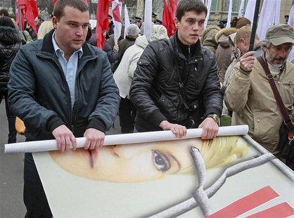 Opposition supporters roll a banner with the portrait of jailed former prime minister Yulia Tymoshenko after a rally in front of the Parliam Opposition supporters roll a banner with the portrait of jailed former prime minister Yulia Tymoshenko after a rally in front of the Parliam