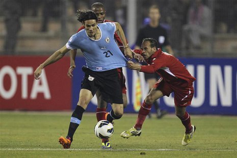 Edinson Cavani of Uruguay (L) fights for the ball with Adnan Adous of Jordan during their World Cup qualifying playoff first leg soccer matc Edinson Cavani of Uruguay (L) fights for the ball with Adnan Adous of Jordan during their World Cup qualifying playoff first leg soccer matc