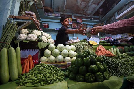 A vendor accepts money from a customer at his vegetable stall at a wholesale fruit and vegetable market in Mumbai April 14, 2013. REUTERS/Vi A vendor accepts money from a customer at his vegetable stall at a wholesale fruit and vegetable market in Mumbai April 14, 2013. REUTERS/Vi