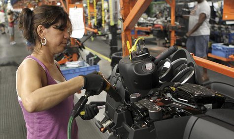 A worker installs parts onto the dashboard for the new Chevrolet Cruze car as it moves along the assembly line at the General Motors Cruze a A worker installs parts onto the dashboard for the new Chevrolet Cruze car as it moves along the assembly line at the General Motors Cruze a