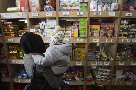 A woman carrying her son stands in front of a food shelf as she shops at a supermarket in northern Tehran, December 12, 2011. REUTERS/Mortez A woman carrying her son stands in front of a food shelf as she shops at a supermarket in northern Tehran, December 12, 2011. REUTERS/Mortez