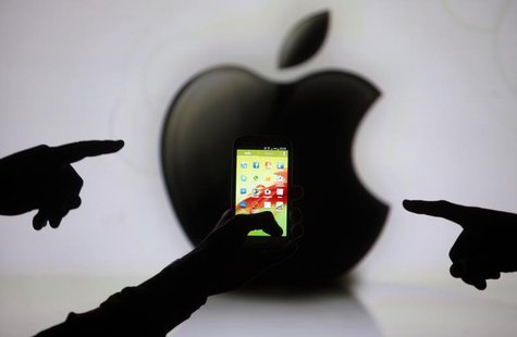 Men are silhouetted against a video screen with an Apple Inc logo as they pose with a Samsung Galaxy S3 smartphone in this photo illustratio Men are silhouetted against a video screen with an Apple Inc logo as they pose with a Samsung Galaxy S3 smartphone in this photo illustratio