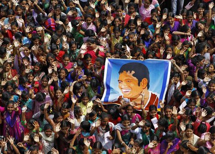 School children wave as they hold a poster of Indian cricketer Sachin Tendulkar at an event to honour him inside a school in the southern In School children wave as they hold a poster of Indian cricketer Sachin Tendulkar at an event to honour him inside a school in the southern In