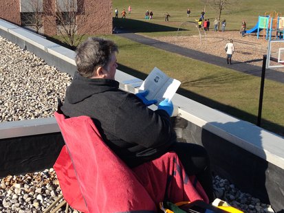 Random Lake Elementary Principal Sandra Mountain enjoys a book on the school's roof. Random Lake Elementary Principal Sandra Mountain enjoys a book on the school's roof.