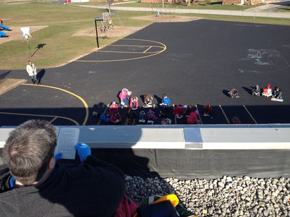 Random Lake third graders read in the playground to encourage Principal Sandra Mountain while she reads on the roof for National Young Reader's Week. Random Lake third graders read in the playground to encourage Principal Sandra Mountain while she reads on the roof for National Young Reader's Week.