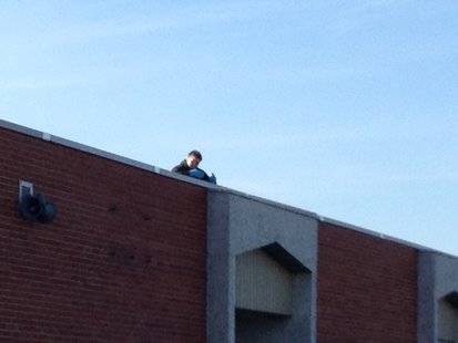 A view of Random Lake Elementary Principal Sandra Mountain from the ground as she reads on the roof, part of a challenge for National Young Reader's Week. A view of Random Lake Elementary Principal Sandra Mountain from the ground as she reads on the roof, part of a challenge for National Young Reader's Week.
