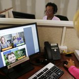 Janet Perez (R) oversees specialists (top) as they help callers and potential customers find health insurance at a customer contact and call Janet Perez (R) oversees specialists (top) as they help callers and potential customers find health insurance at a customer contact and call