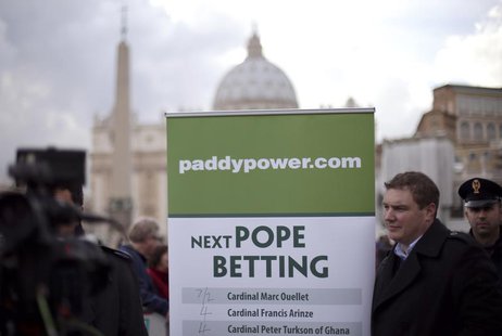 A man holds an advertisement for Paddy Power, an Irish bookmaker, in front of St Peter's square, outside the Vatican February 12, 2013. REUT A man holds an advertisement for Paddy Power, an Irish bookmaker, in front of St Peter's square, outside the Vatican February 12, 2013. REUT