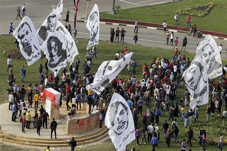 People wave banners depicting people who died in previous Egyptian revolutions around a monument, erected in honour of the victims, draped w People wave banners depicting people who died in previous Egyptian revolutions around a monument, erected in honour of the victims, draped w