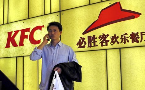 A man talks on his mobile phone in front of the logos of KFC and Pizza Hut, both restaurants under Yum Brands, in Shanghai, March 6, 2013. R A man talks on his mobile phone in front of the logos of KFC and Pizza Hut, both restaurants under Yum Brands, in Shanghai, March 6, 2013. R