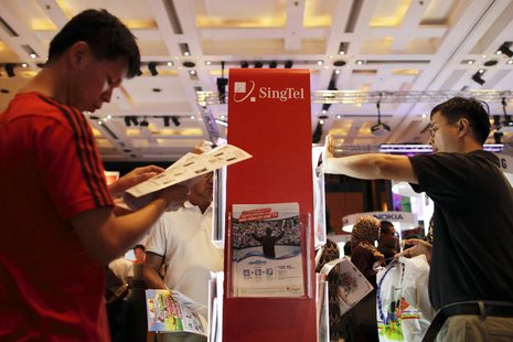 People look at brochures for deals on offer at the SingTel roadshow during the annual IT Show technology fair in Singapore March 10, 2012. R People look at brochures for deals on offer at the SingTel roadshow during the annual IT Show technology fair in Singapore March 10, 2012. R