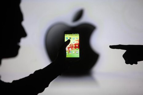 Men are silhouetted against a video screen with an Apple Inc logo as they pose with a Samsung Galaxy S3 smartphone in this photo illustratio Men are silhouetted against a video screen with an Apple Inc logo as they pose with a Samsung Galaxy S3 smartphone in this photo illustratio