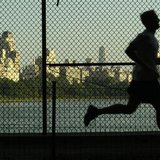 A man jogs along a path around the Central Park Reservoir with the buildings of Fifth Avenue in the backround in New York's famed Central Pa A man jogs along a path around the Central Park Reservoir with the buildings of Fifth Avenue in the backround in New York's famed Central Pa