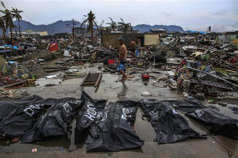 People walk past body bags in Tacloban November 23, 2013. REUTERS/Athit Perawongmetha People walk past body bags in Tacloban November 23, 2013. REUTERS/Athit Perawongmetha