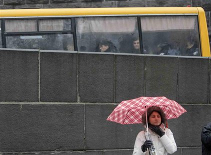 Police are seen in a bus while a protester stands with her umbrella during a rally in support of EU integration in front of the Ukrainian ca Police are seen in a bus while a protester stands with her umbrella during a rally in support of EU integration in front of the Ukrainian ca