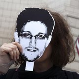 A woman holds a portrait of former U.S. spy agency contractor Edward Snowden in front of her face as she stands in front of the U.S. embassy A woman holds a portrait of former U.S. spy agency contractor Edward Snowden in front of her face as she stands in front of the U.S. embassy