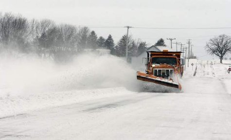 A snowplow clears a road from a past storm A snowplow clears a road from a past storm