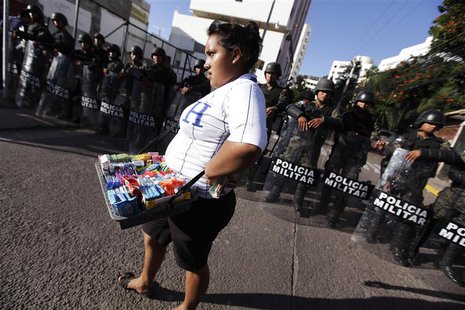 A street vendor walks past a police blockade during a protest by supporters of presidential candidate Xiomara Castro in Tegucigalpa November A street vendor walks past a police blockade during a protest by supporters of presidential candidate Xiomara Castro in Tegucigalpa November