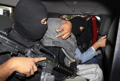 A police officer drapes a jacket over the head of a suspect believed to be Edgar Jimenez (C), also known as "El Ponchis", after escorting hi A police officer drapes a jacket over the head of a suspect believed to be Edgar Jimenez (C), also known as "El Ponchis", after escorting hi