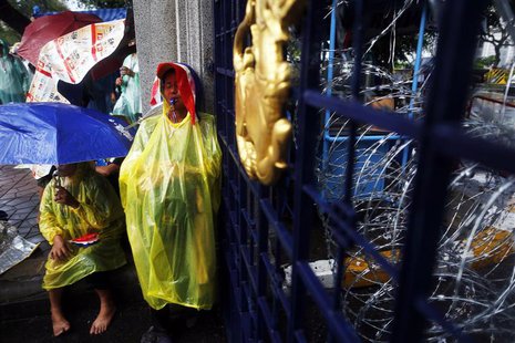Anti-government protesters protect themselves from the rain as they stay at the gates of the Interior Ministry in Bangkok November 26, 2013. Anti-government protesters protect themselves from the rain as they stay at the gates of the Interior Ministry in Bangkok November 26, 2013.