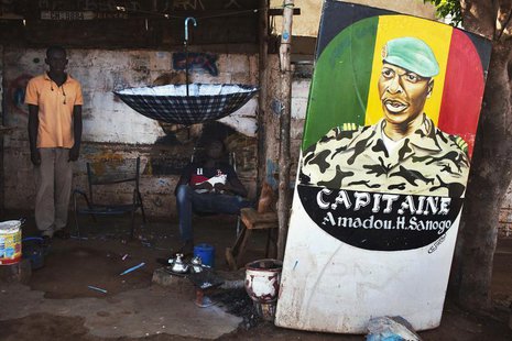 Men sit next to a painting of the ex-junta leader Amadou Haya Sanogo in Bamako July 16, 2013. Mali will be holding presidential election on Men sit next to a painting of the ex-junta leader Amadou Haya Sanogo in Bamako July 16, 2013. Mali will be holding presidential election on