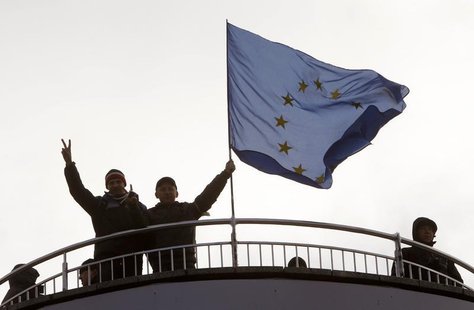 Protesters gesture as they stand near an EU flag during a demonstration in support of EU integration at Independence Square in Kiev November Protesters gesture as they stand near an EU flag during a demonstration in support of EU integration at Independence Square in Kiev November