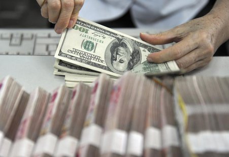 A clerk counts U.S. dollar banknotes after counting Chinese 100 Yuan banknotes at a branch of the Agricultural Bank of China in Qionghai, Ch A clerk counts U.S. dollar banknotes after counting Chinese 100 Yuan banknotes at a branch of the Agricultural Bank of China in Qionghai, Ch