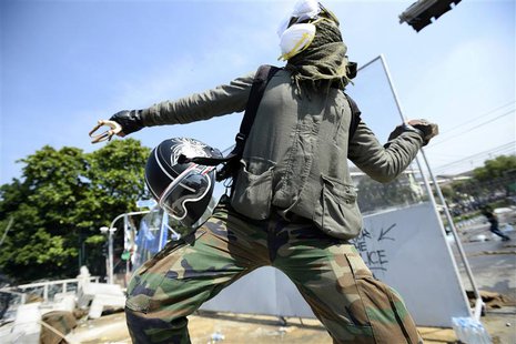An anti-government protester throws a rock at Thai riot police as they attempt to remove barricades outside Government House in Bangkok Dece An anti-government protester throws a rock at Thai riot police as they attempt to remove barricades outside Government House in Bangkok Dece